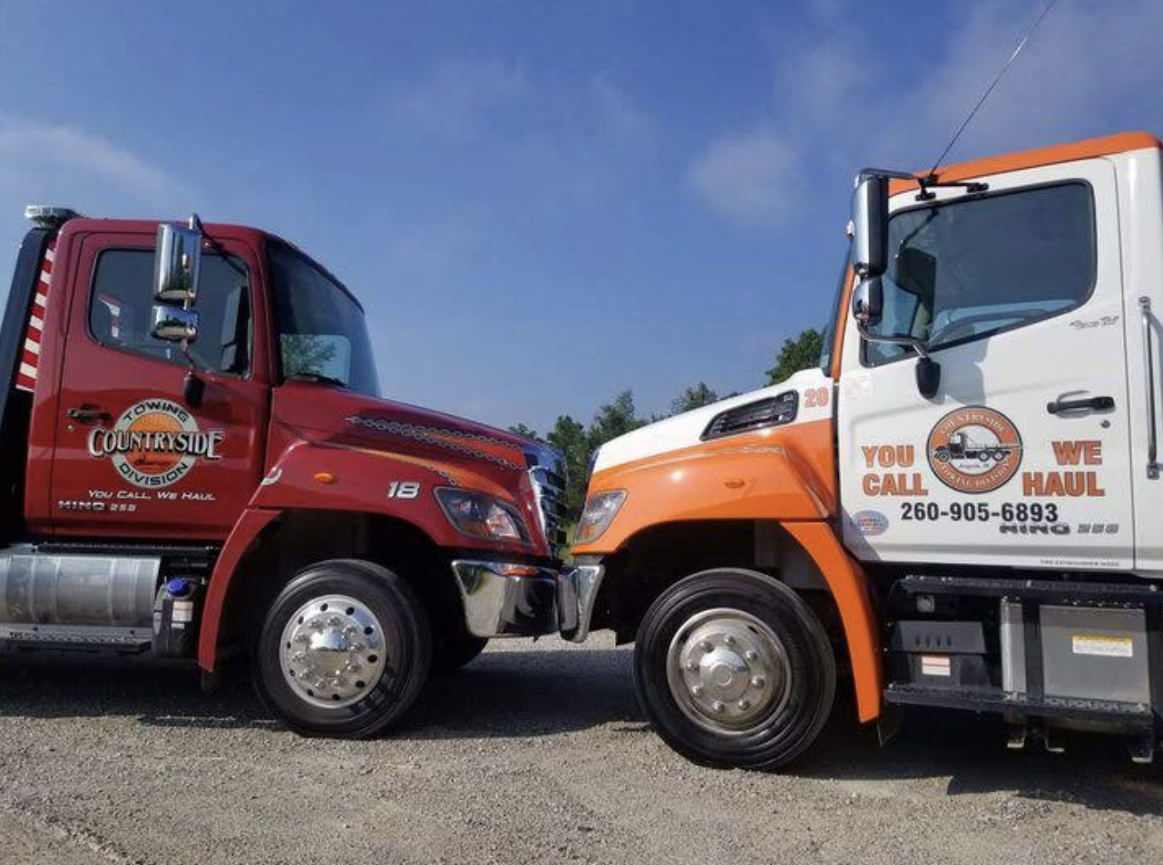 Two Countryside Towing flatbed trucks parked side by side in Angola, Indiana